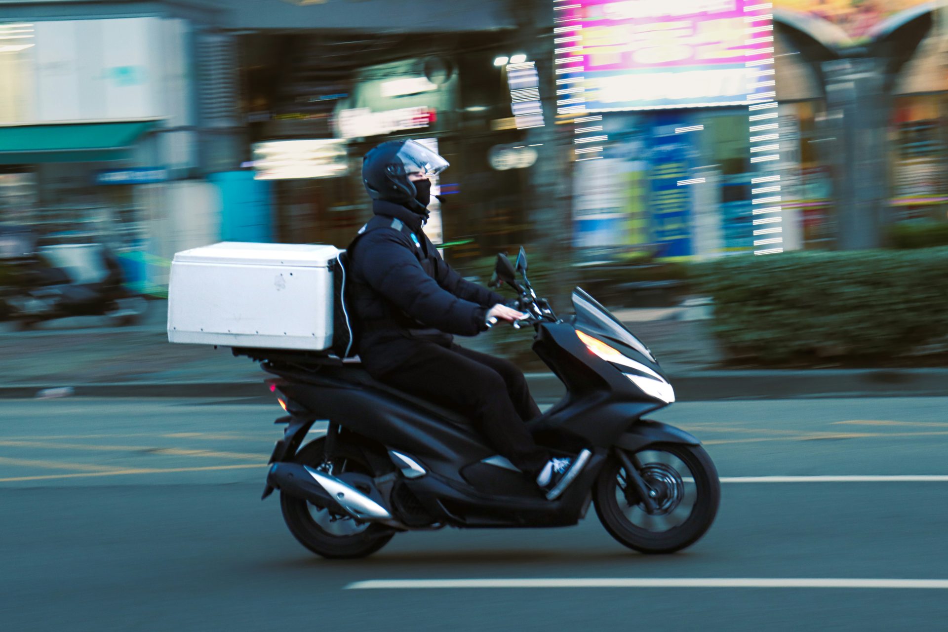 a man riding a scooter with a box on the back of it